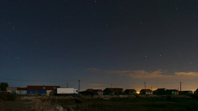 Night time lapse of the oyster and fisher huts at the port in Saint Trojan les Bains at low tide with stars moving on the clear sky.