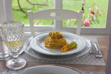 lunch set table in a bay window with zucchini floers spaghetti