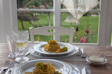 lunch set table in a bay window with zucchini floers spaghetti - 532048111