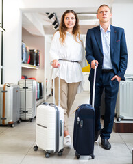 Portrait of respectable couple with suitcases in a haberdashery store