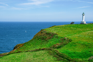 Fototapeta na wymiar Cabo de Lastres lighthouse in Luces-Colunga, in Asturias (Spain), surrounded by green meadows on the Cantabrian Sea