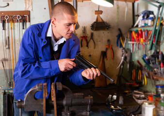 Gunsmith disassembles and repairs pistol in a weapons workshop