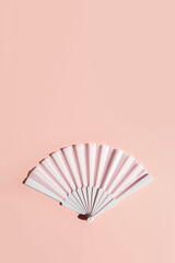 White fan on beige background with hard shadows. Minimal concept of menopause and female hot flashes. Vertical banner, copy space - obrazy, fototapety, plakaty