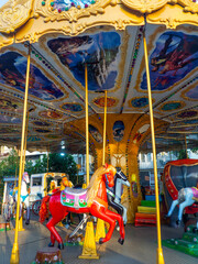 Fototapeta na wymiar Carousel with horses. Bright attraction for children. Entertainment in the park. Toy horses. Driving in a circle. Children's fun.