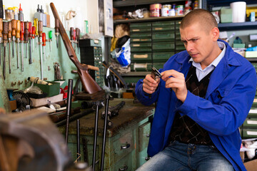 Man measures rifle detail with a caliper