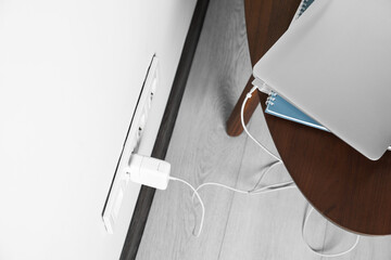 Fototapeta na wymiar Electric power outlet sockets with charger on white wall, above view