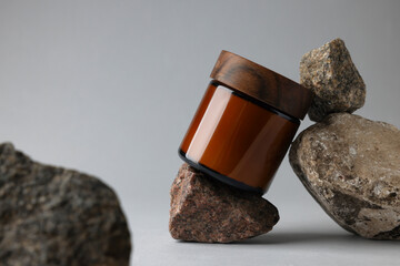 Glass jar and stones on grey background, closeup