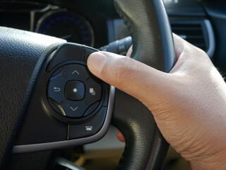 closeup of hand pushing button on the steering wheel in a modern car.	