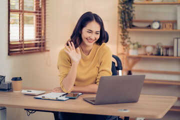 Fototapeta premium Portrait of a beautiful Asian woman looking at laptop screen while sitting at working desk in the office