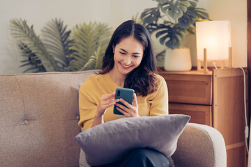 Young Asian woman relax on cozy sofa furniture in living room using browsing Internet on tablet, Asian girl lying resting on comfortable couch at home watching movie or video on pad.