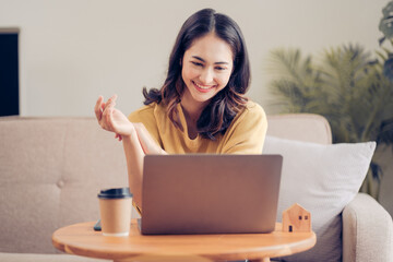 Confident pretty asian business woman working with laptop while doing some paperwork at home