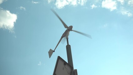 A small wind generator on a pole against the sky. Production of electricity in the field.