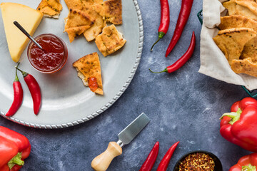 Top down view of hot pepper jelly in a jar served with crispy crackers.
