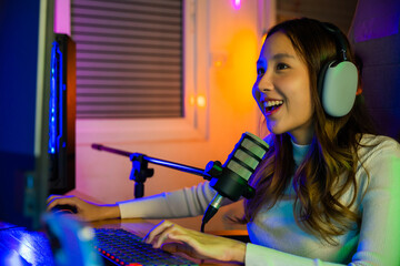 Asian young gamer woman wear headphones playing video games online on computer she live stream and...