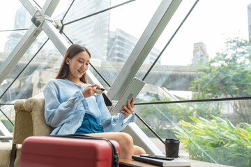 Young asian beautiful female lady making a payment for an online shopping purchase via her digital tablet easily and successful while sitting in a cafe