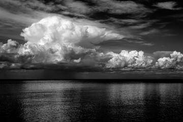 Dramatic black and white image of storm clouds above a calm lake. 