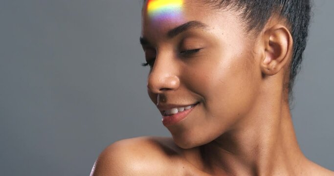 Natural face, beauty and rainbow light or ray on happy and proud woman against a grey background. Skincare, lgbtq and gender pride or expression of a strong black lesbian female feeling sensual