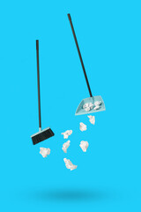 Levitating dustpan, paper and cleaning brush on a blue background.