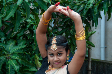a teenage girl practicing bharatnatyam in nature