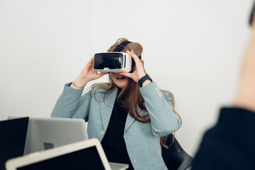 Businesspeople wearing VR goggles while working with hands reaching out to touch something in virtual world.