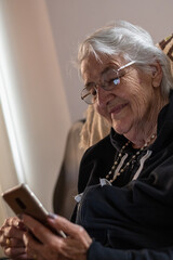 elderly woman grandmother writing on the phone to her grandchildren