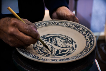 Thai craftsmanship technician or professional ceramicist drawing  and painting color on handmade...