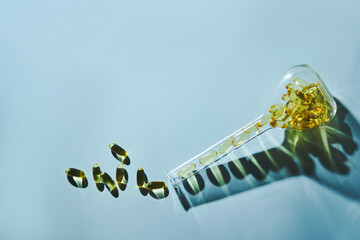 Capsules of omega-3 fatty acids on a blue background in a flask. The concept of medicine and a...