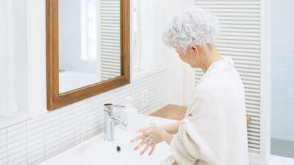 手を洗うシニア女性 © polkadot