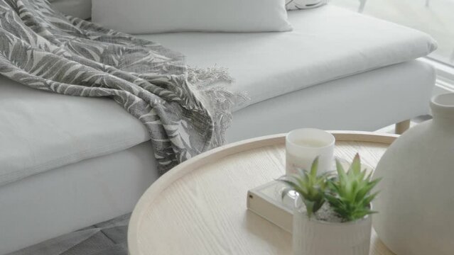 Detail shot of a decorated coffee table and couch beside the floor to ceiling windows in the living area of a condominium unit during a sunny afternoon.