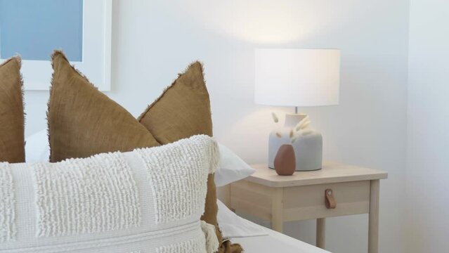 Focus change from pillow to nightstand and lamp beside the bed in a condominium bedroom during a sunny day