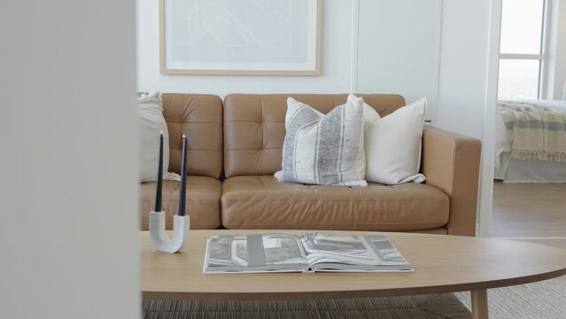 Straight angle dolly shot of the living area in a high ceiling penthouse condominium unit showing the details of the leather sofa and coffee table during a sunny day