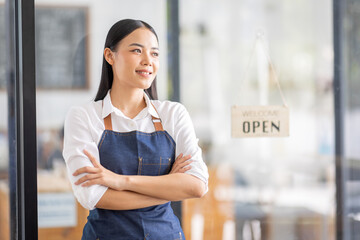 Asian woman is a waitress in an apron, the owner of the cafe stands at the door with a sign Open waiting for customers. Small business  cafes and restaurants concept,