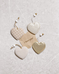 Valentines day concept. Soft toy hearts from linen cloth with gold color striped or dots on marble background. Valentine as torn paper craft with text i love you. Paper mock up for text