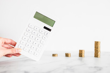 growing stacks of coins next to calculator representing increasingly expensive prices or savings and compound interests increasing, finance and money concept