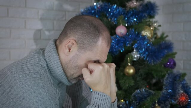 Man pondering about Christmas holidays. A man without family sits in loneliness and celebrate the Christmas in the room.