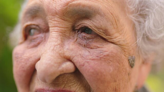 Blind portrait, retirement and senior woman thinking in garden, relax in nature with idea and eye problem against green background with bokeh. Elderly person with cataract vision blurred in village