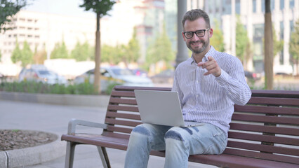 Fototapeta premium Agree Young Adult Man Shaking Head in Approval while Sitting on Bench Outdoor
