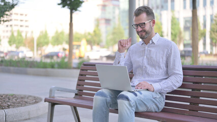 Young Adult Man Talking on Video Call while Sitting Outdoor on Bench