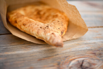 A hand-baked tortilla lies in a paper bag on a wooden table. Kraft. National bread. Eco-friendly...