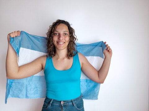 young Argentinian woman cheering for her team, waving a flag 