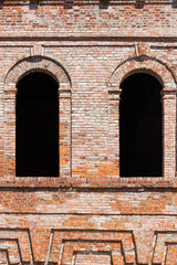 Broken semicircular windows in an old brick building.