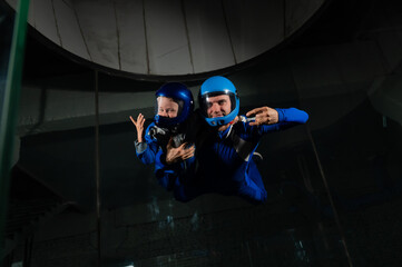 A man teaches a boy to fly in a wind tunnel. Lack of gravity.
