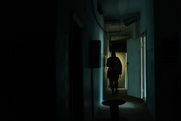 Man explorer with flashlight indoor corridor of ruined industrial building factory, horror and...