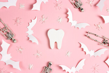 White tooth with Halloween decorations on pink background. Dentist Halloween concept.