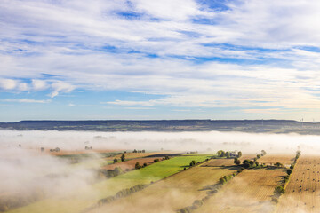 Rural landscape view with tree lined fields and mist