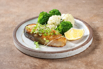 Fried salmon steaks with lemon butter sauce garnish with micro greens.