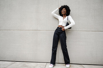 Fototapeta Black woman posing in front of a gray concrete wall obraz