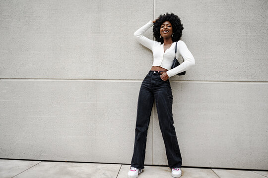 Black woman posing in front of a gray concrete wall