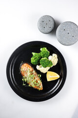 Fried salmon steaks with lemon butter sauce garnish with micro greens.