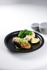 Fried salmon steaks with lemon butter sauce garnish with micro greens.